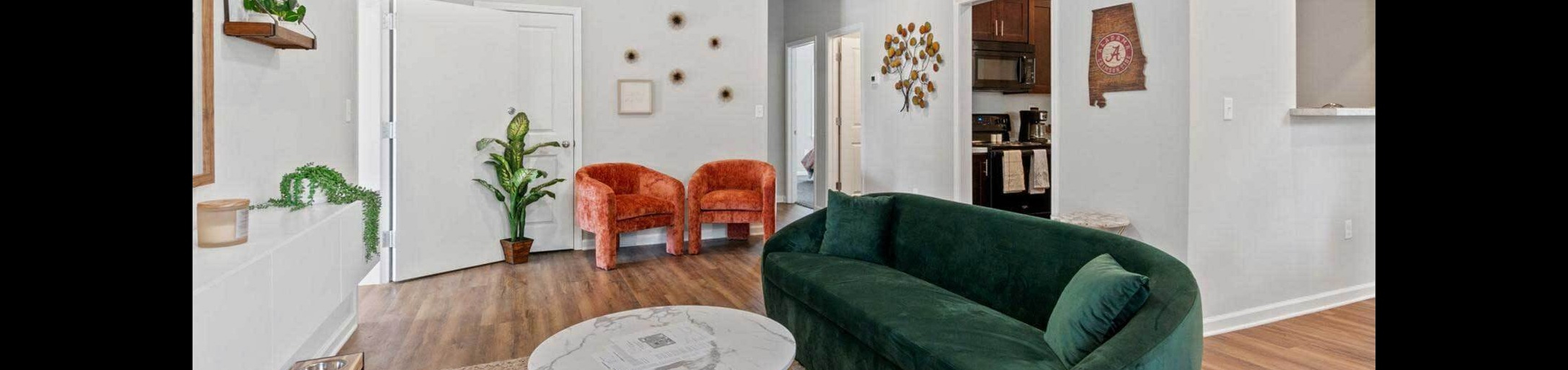 Chic living room with stylish green velvet sofa, vibrant orange chairs, and elegant decor creating a warm and inviting atmosphere.