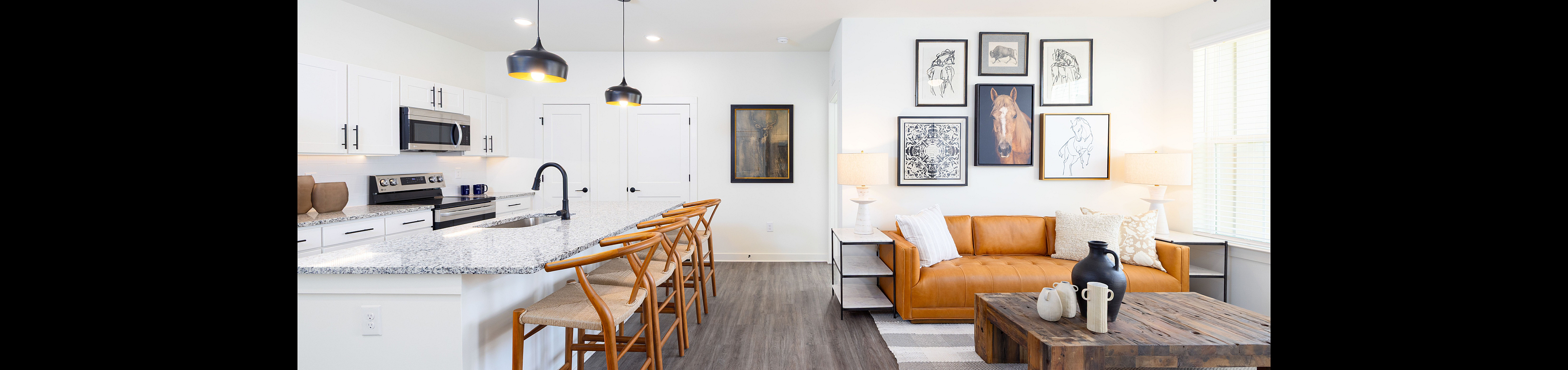 Modern open-plan living area with sleek kitchen, stylish pendant lighting, and inviting leather sofa.
