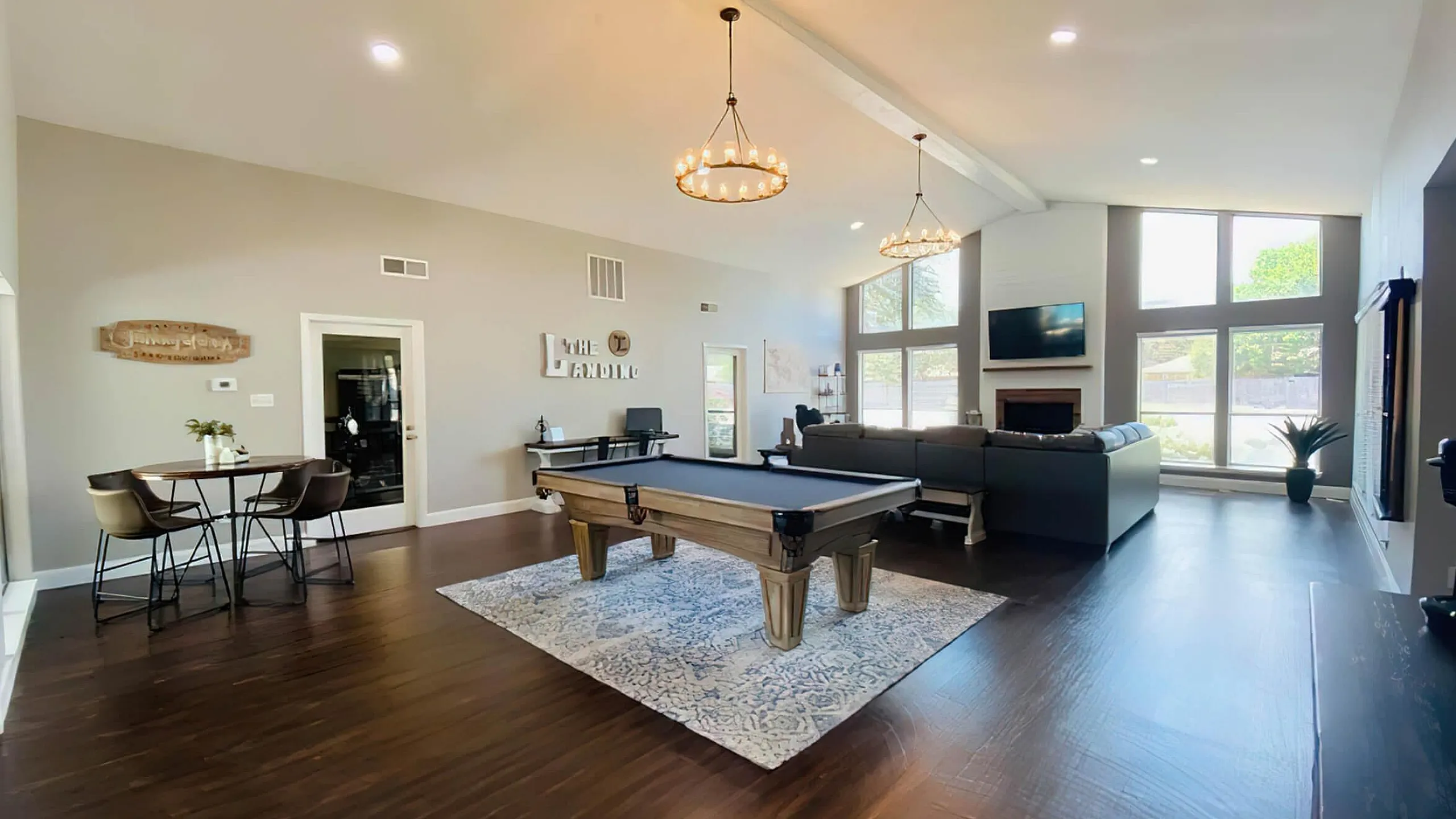 Luxurious clubroom space with high ceilings, featuring a stylish pool table, cozy seating area, and large windows offering abundant natural light.