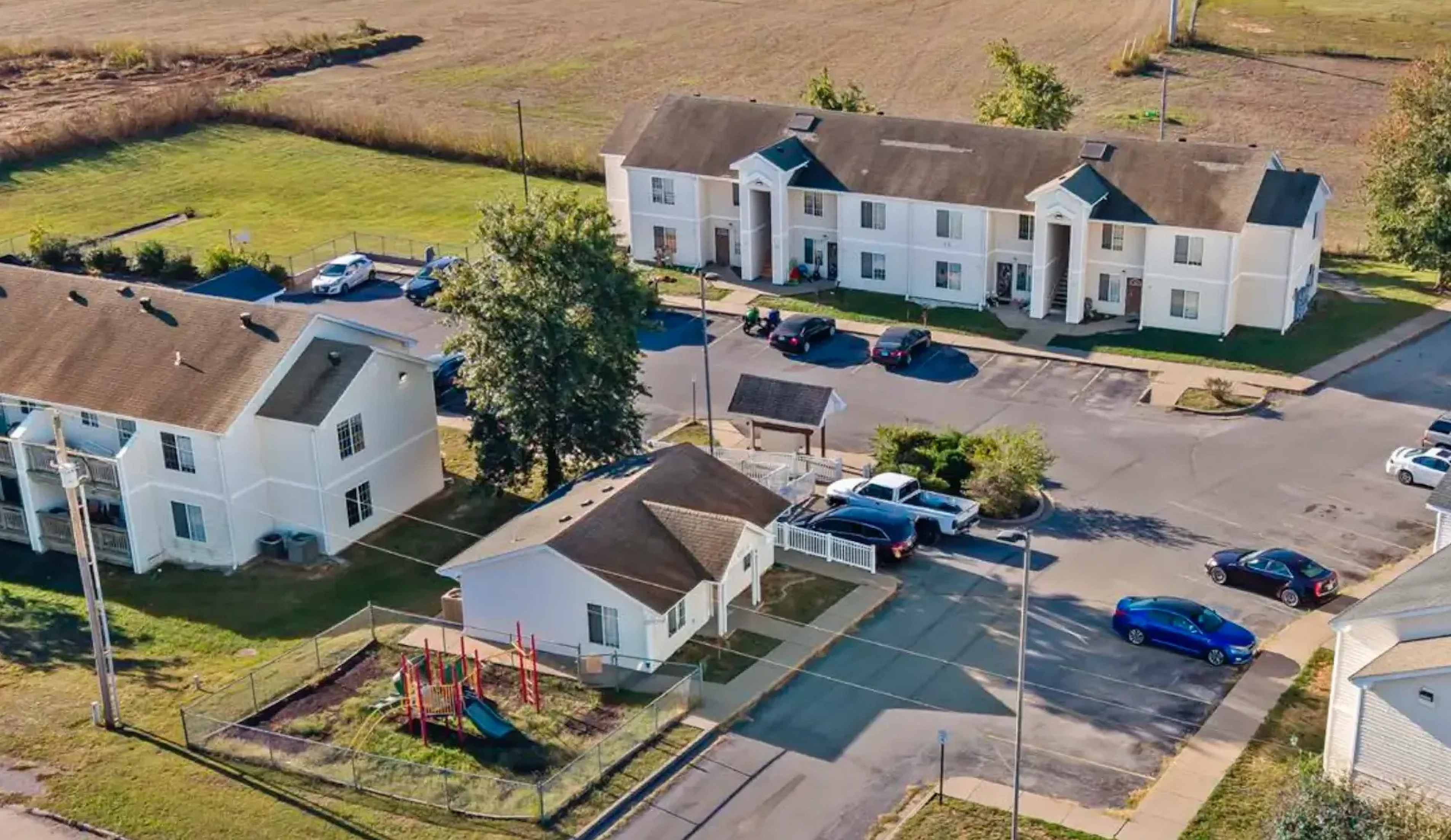 The Pines at Perryville view from above, showcasing the 3 buildings, parking lot, playground, and surrounding fields.