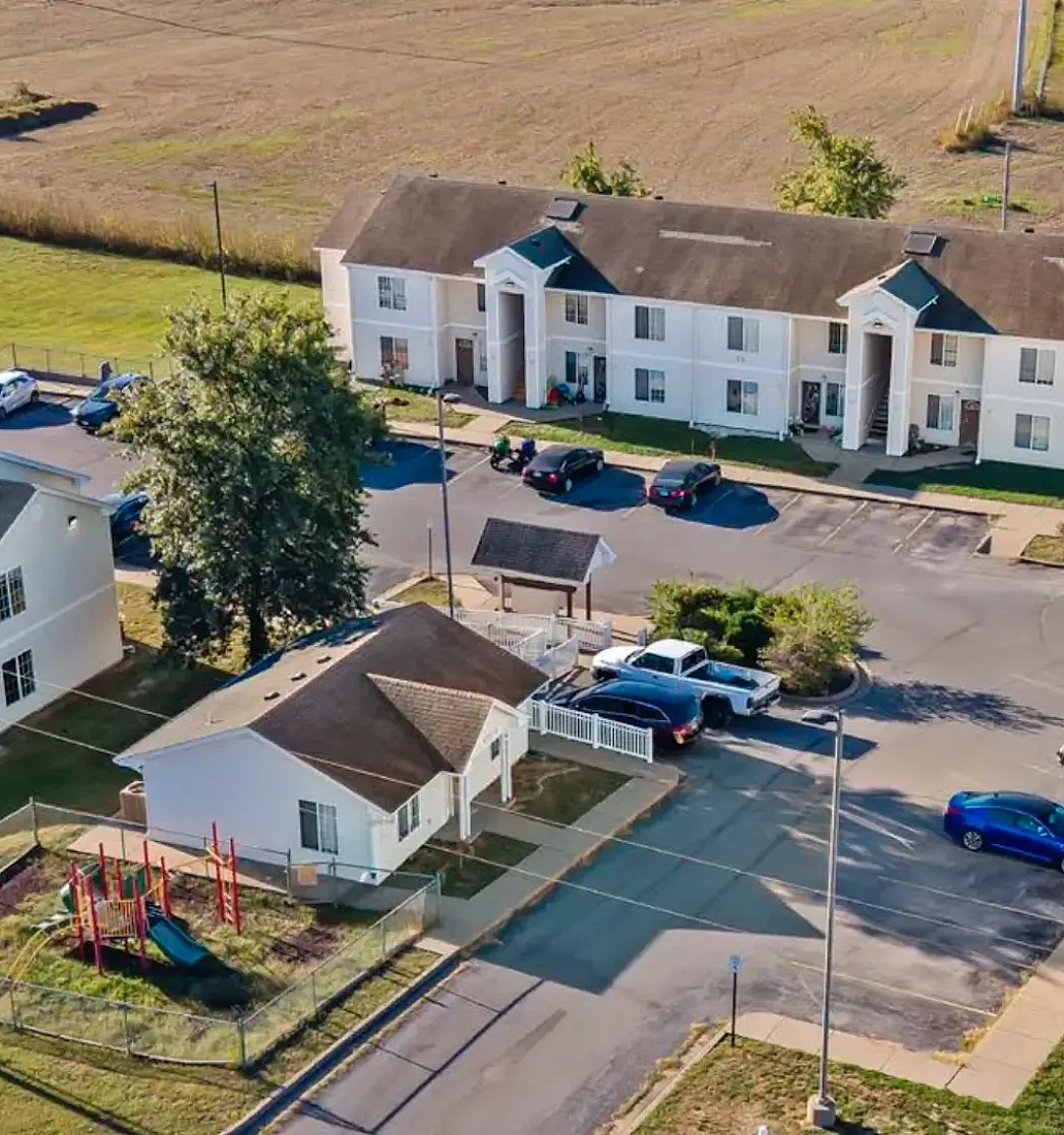 The Pines at Perryville view from above, showcasing the 3 buildings, parking lot, playground, and surrounding fields.