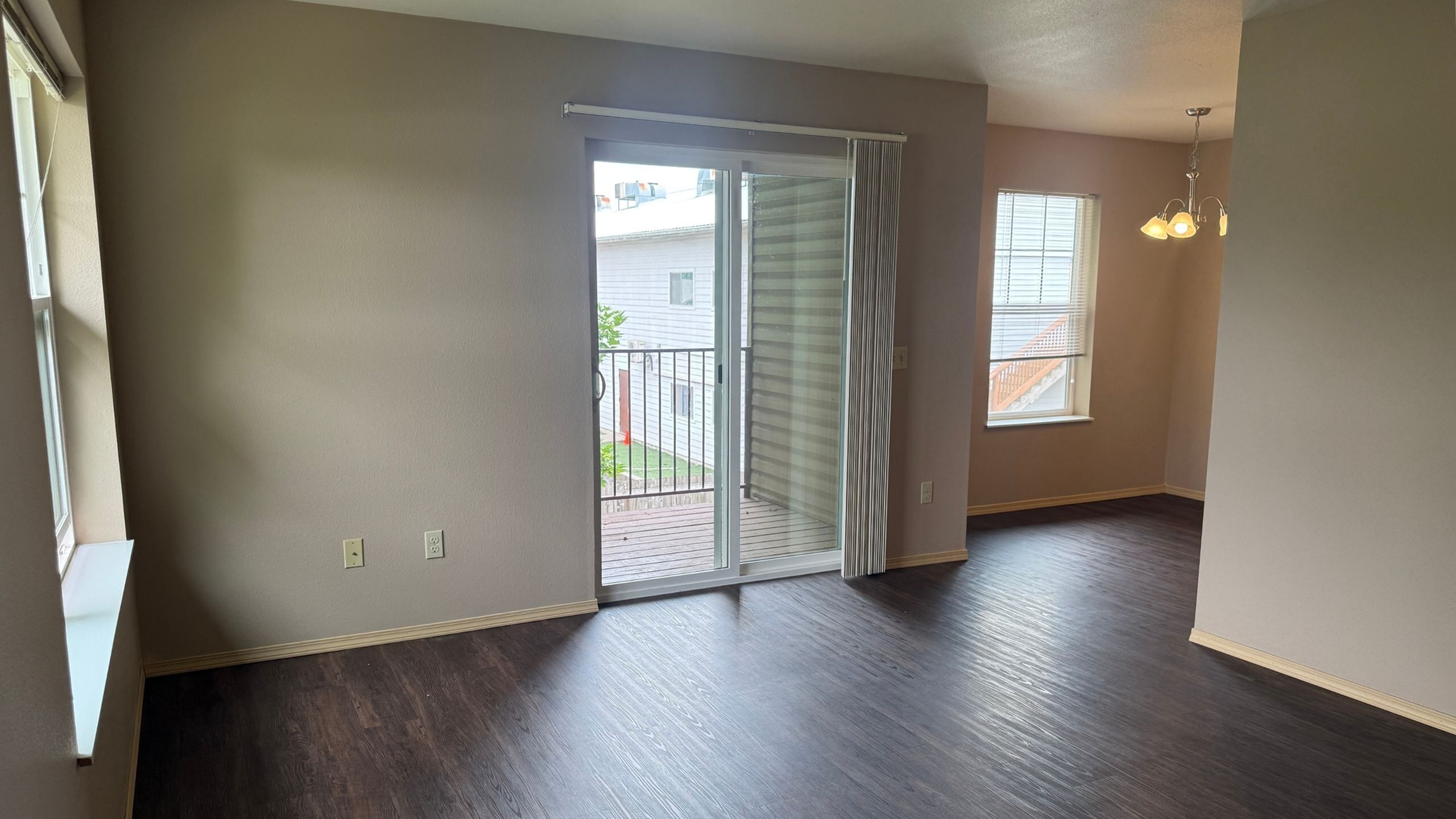 Bright and airy apartment with elegant dark wood flooring, sliding glass doors leading to a charming balcony, and warm neutral walls.