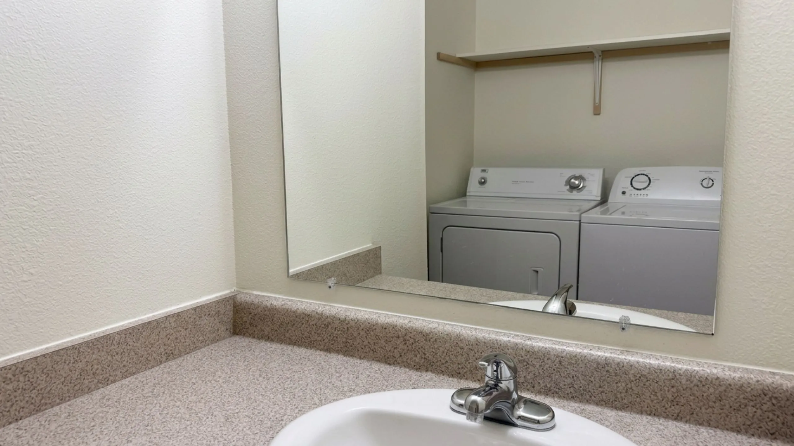 Modern laundry room with washing machine and dryer, reflected in a stylish bathroom mirror.