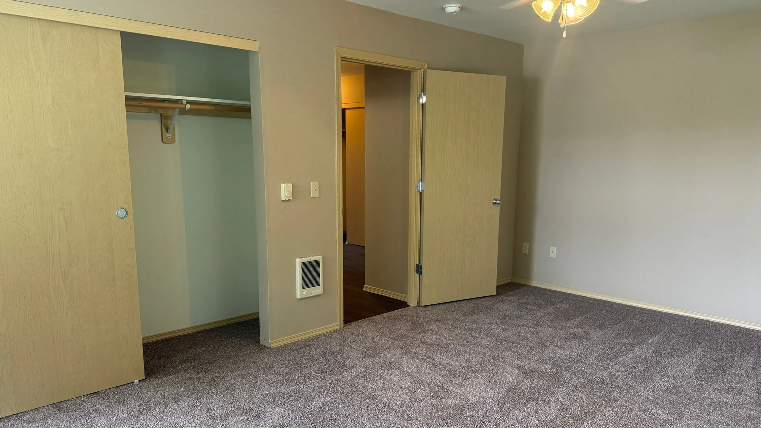 Cozy bedroom with plush carpet, neutral walls, and ample closet space, perfect for relaxation.