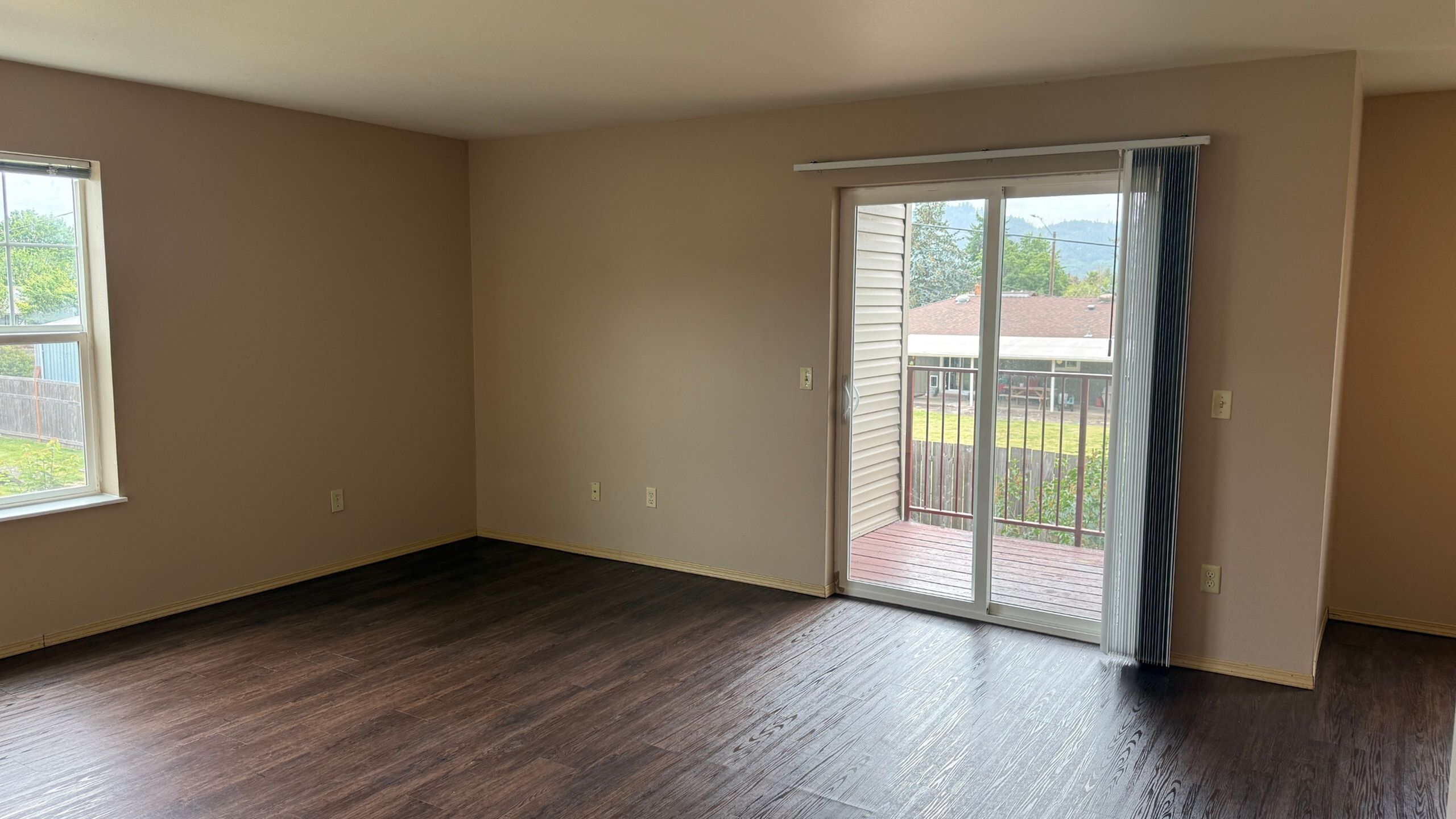 Bright and airy living space with elegant dark wood flooring, large windows, and access to a charming balcony overlooking a serene view.