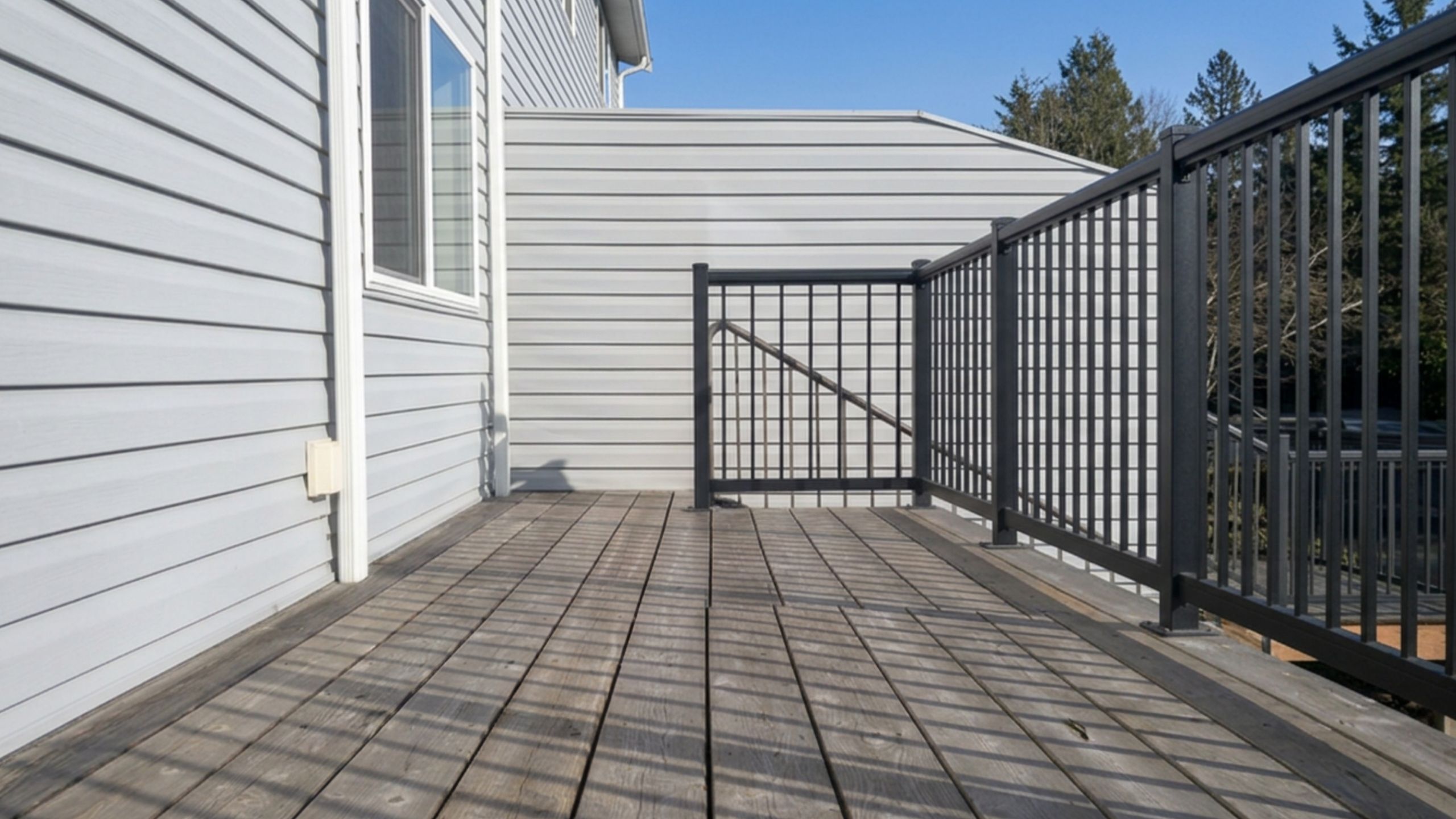 Charming wooden deck with modern railings and a bright, clear sky view.