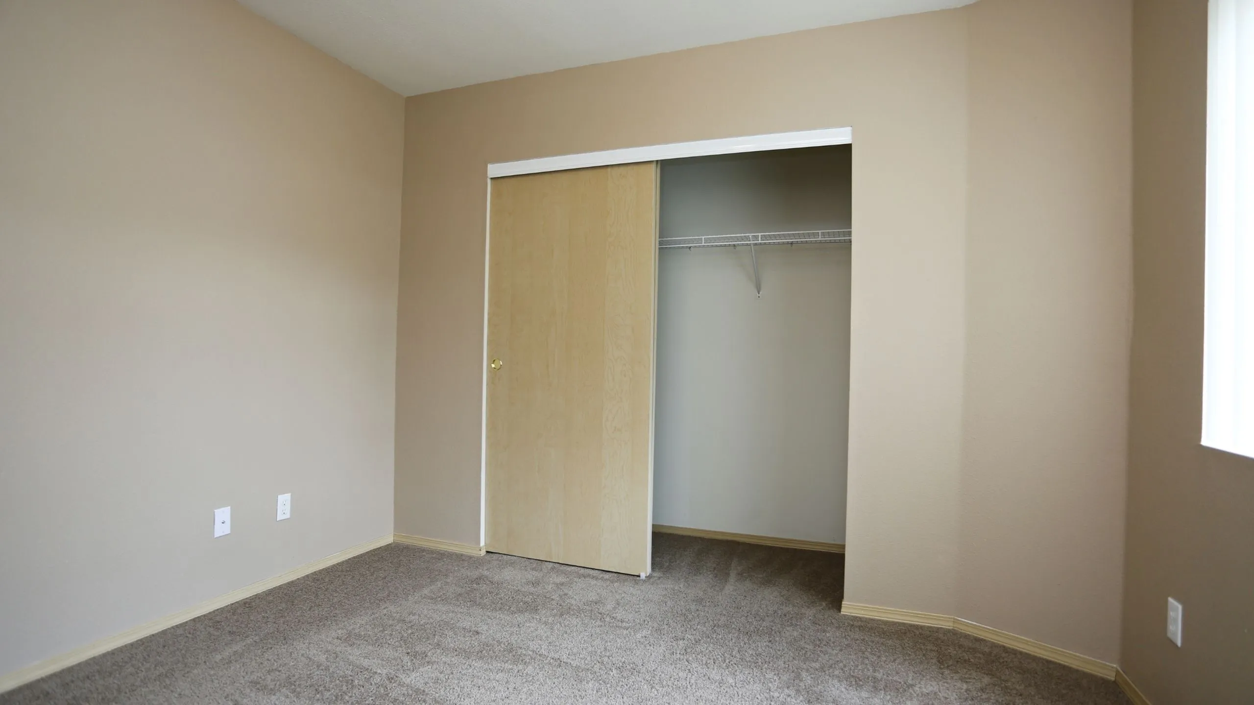 Inviting room with neutral walls, plush carpet, and a spacious sliding door closet perfect for storage.