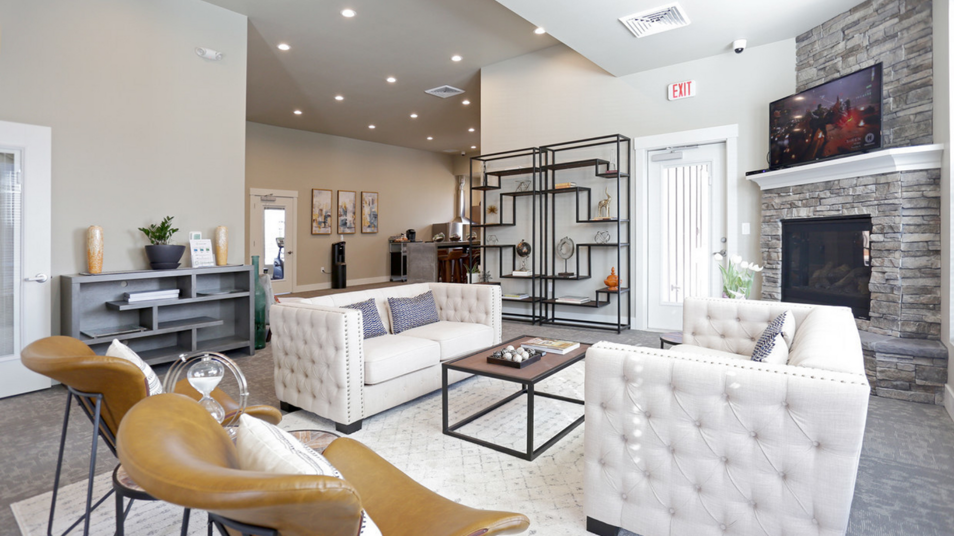 Spacious and stylish living area featuring plush seating, modern shelving, and a cozy stone fireplace.