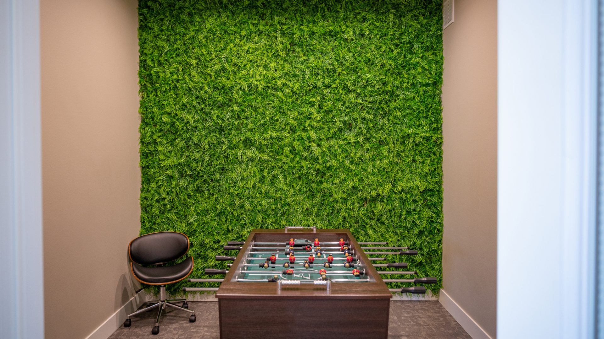 Chic game room with vibrant green wall and sleek foosball table, perfect for entertainment and relaxation.