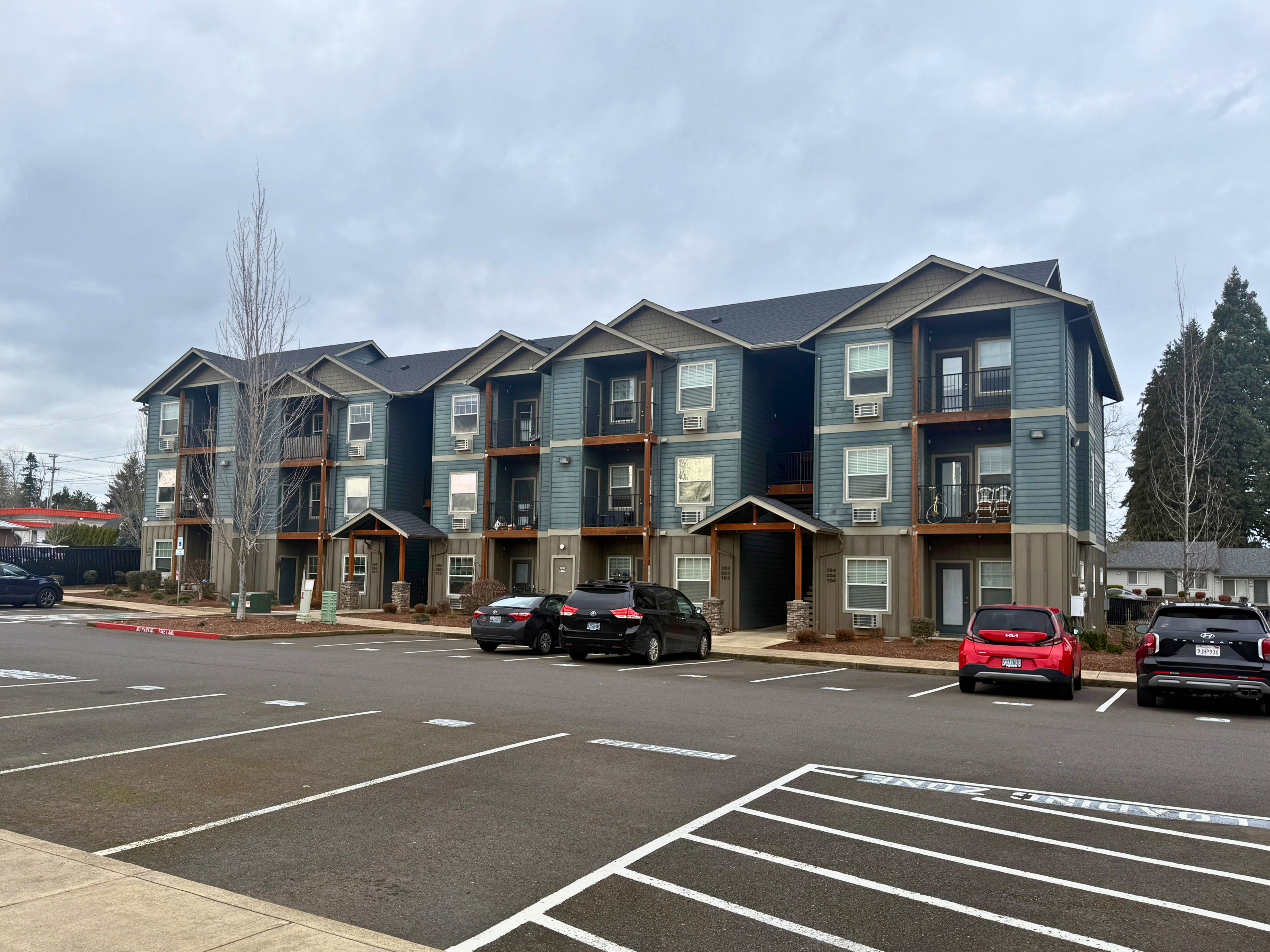Modern three-story apartment complex with attractive balconies, ample parking, and a serene neighborhood setting.