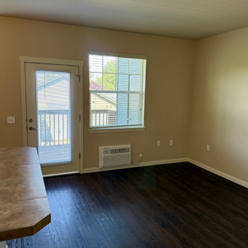 Bright room with a modern air conditioner, large window, and elegant dark wood flooring, offering a cozy and inviting atmosphere.