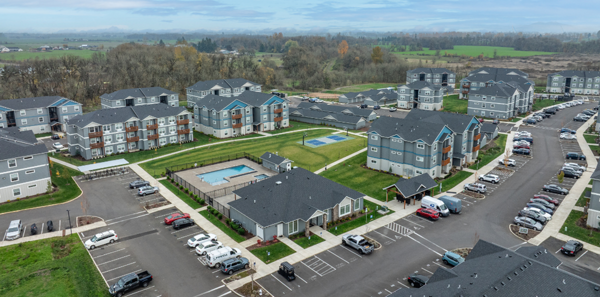 Charming apartment complex with modern buildings, landscaped green spaces, a tennis court, and refreshing swimming pool, nestled in a serene rural setting.