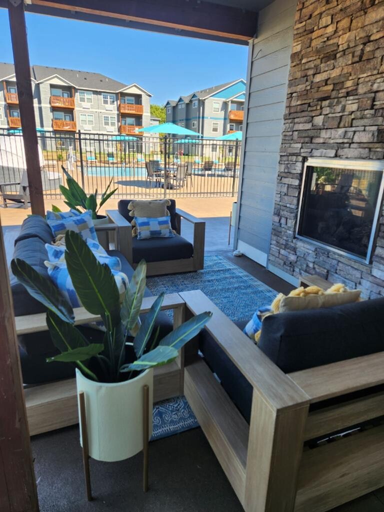 Chic outdoor lounge with cozy seating, stone fireplace, and poolside views, perfect for relaxation and entertaining.