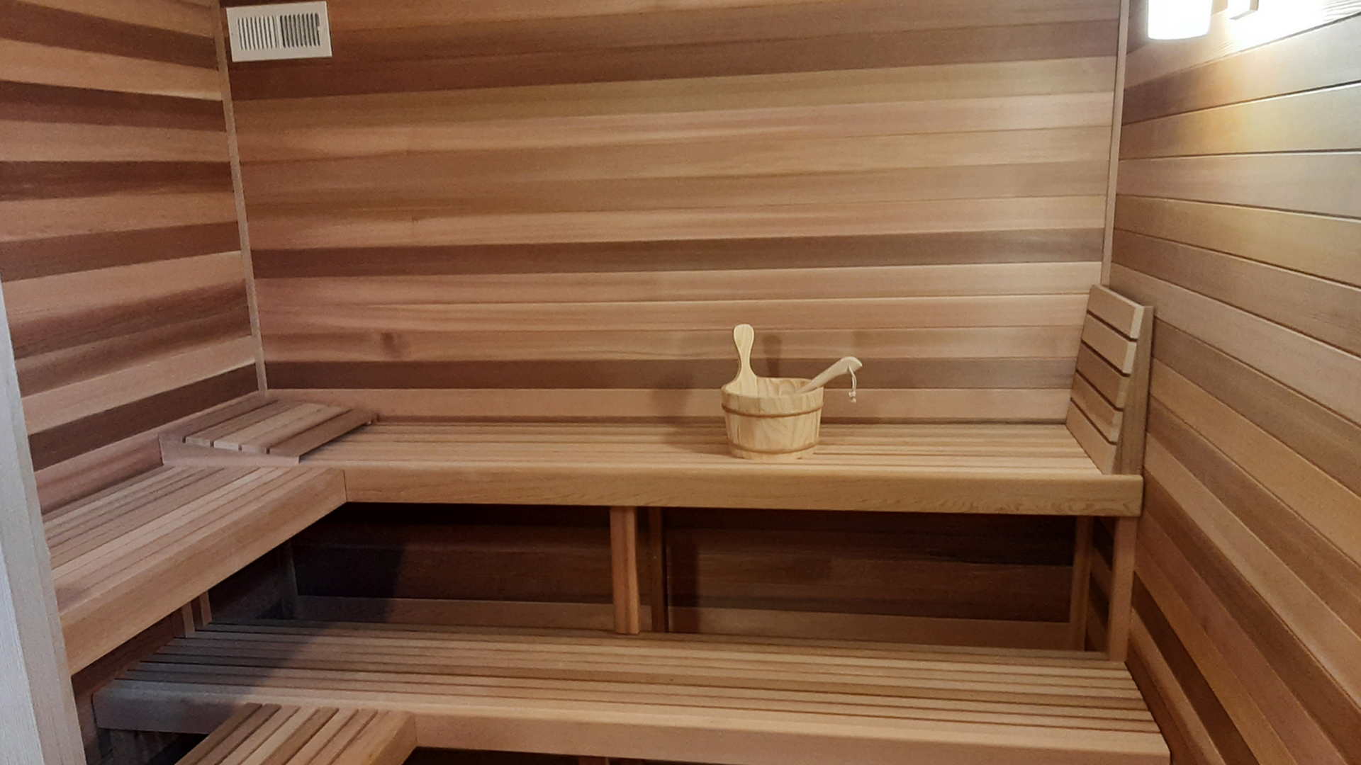 Luxurious wooden sauna with seating and traditional sauna bucket, offering a cozy and relaxing atmosphere.