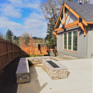 Charming exterior view of a modern house with a spacious patio and built-in stone fire pit, perfect for outdoor entertaining.