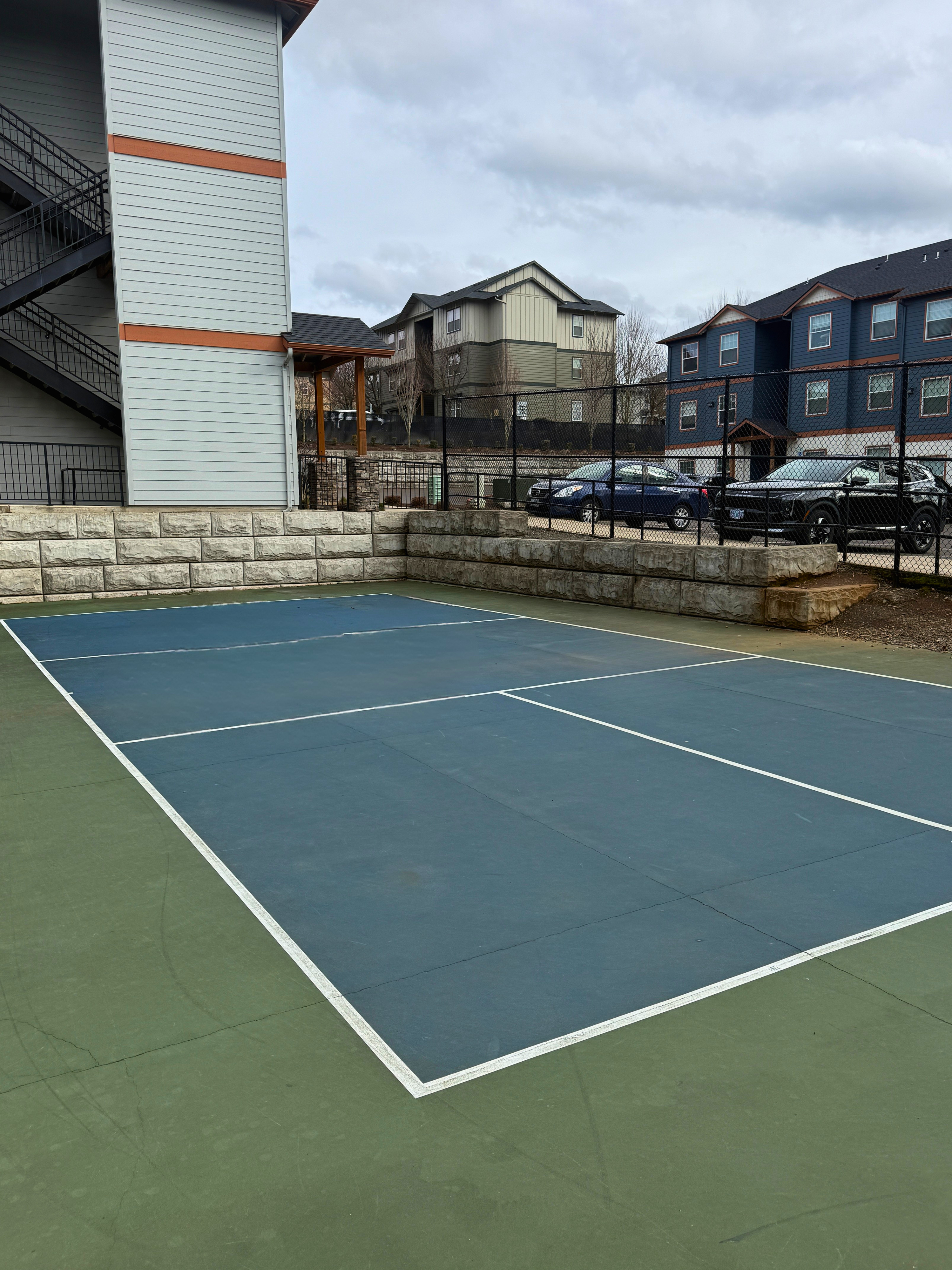 Inviting outdoor tennis court with stylish apartment complex backdrop, ideal for active lifestyles.