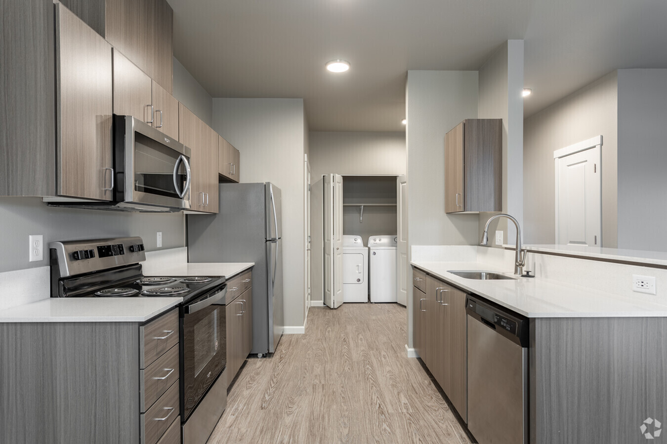 Modern kitchen with sleek wood cabinetry, stainless steel appliances, and in-unit washer and dryer for added convenience.