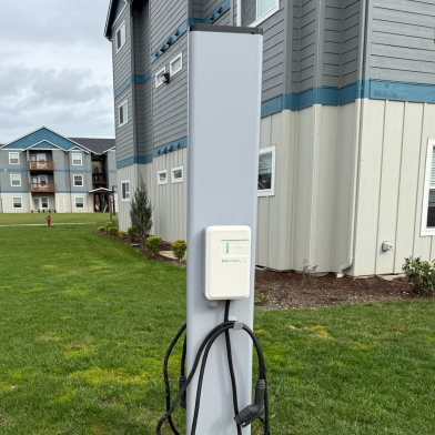 Modern apartment complex with convenient electric vehicle charging station, lush green lawn, and elegant exterior design.