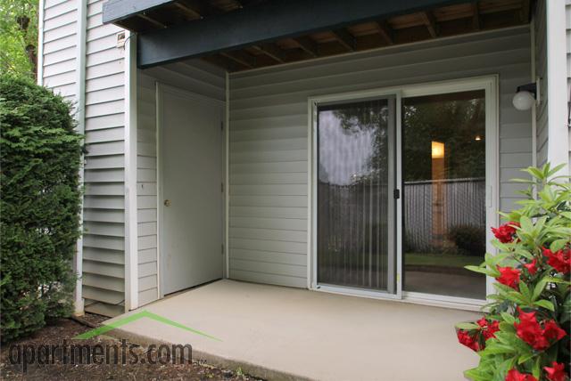 Inviting patio area with sliding glass door, adjacent to lush greenery, offering a serene outdoor escape.
