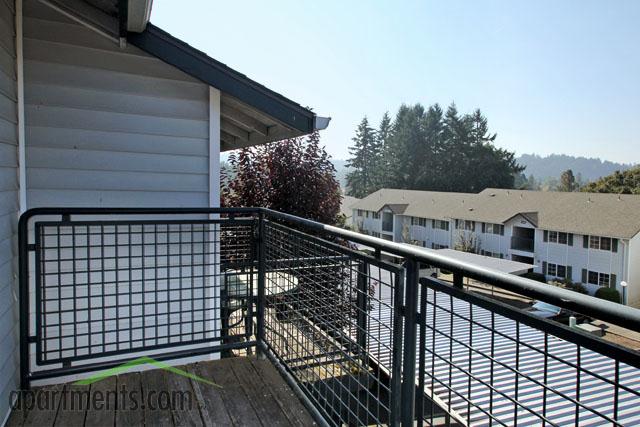 Charming apartment balcony offering serene views of lush greenery and neighboring residential buildings.