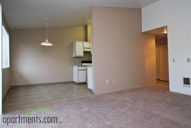 Spacious living and dining area with plush carpeting and natural light, seamlessly connected to a modern kitchen.