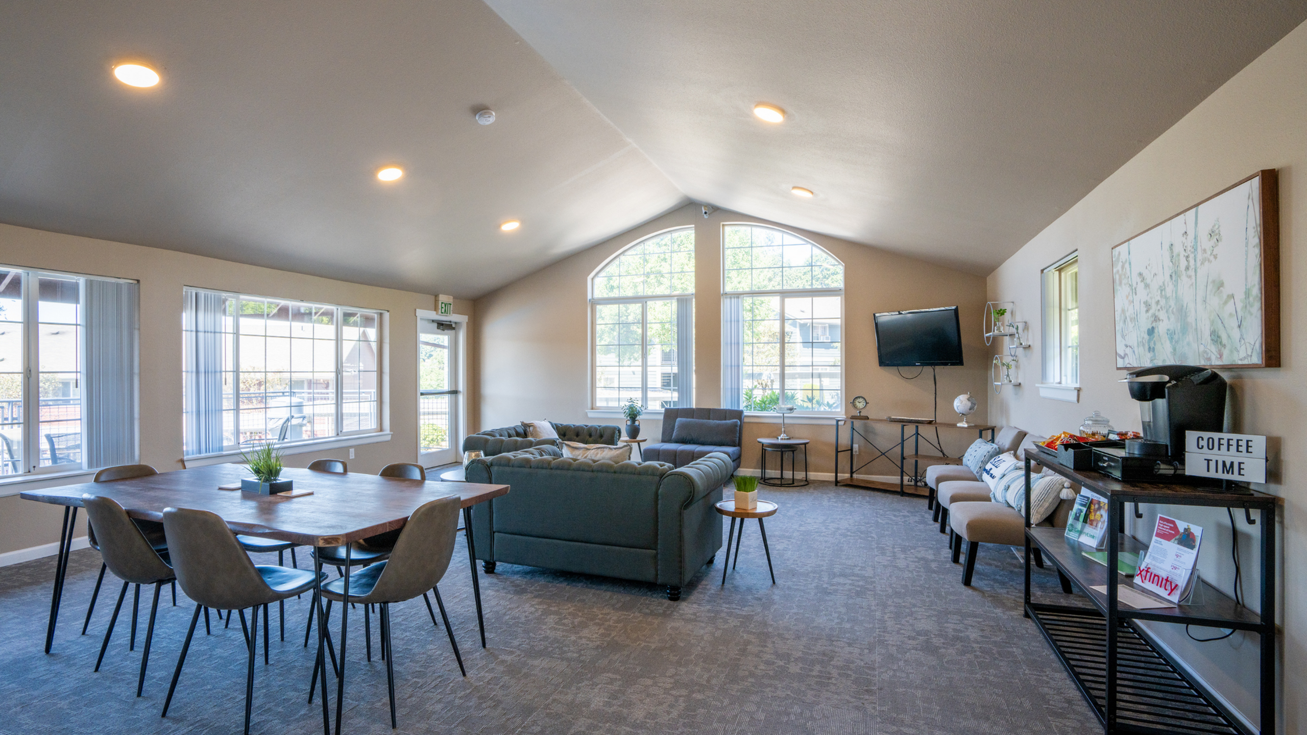 Bright and inviting communal room with large windows, modern sectional sofa, and stylish dining area, perfect for gatherings.