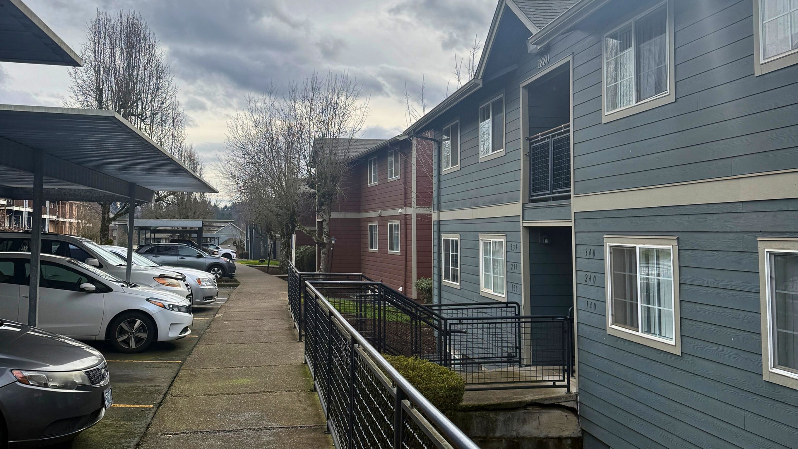 Charming apartment complex with modern architectural design, surrounded by a spacious parking area and lush greenery.