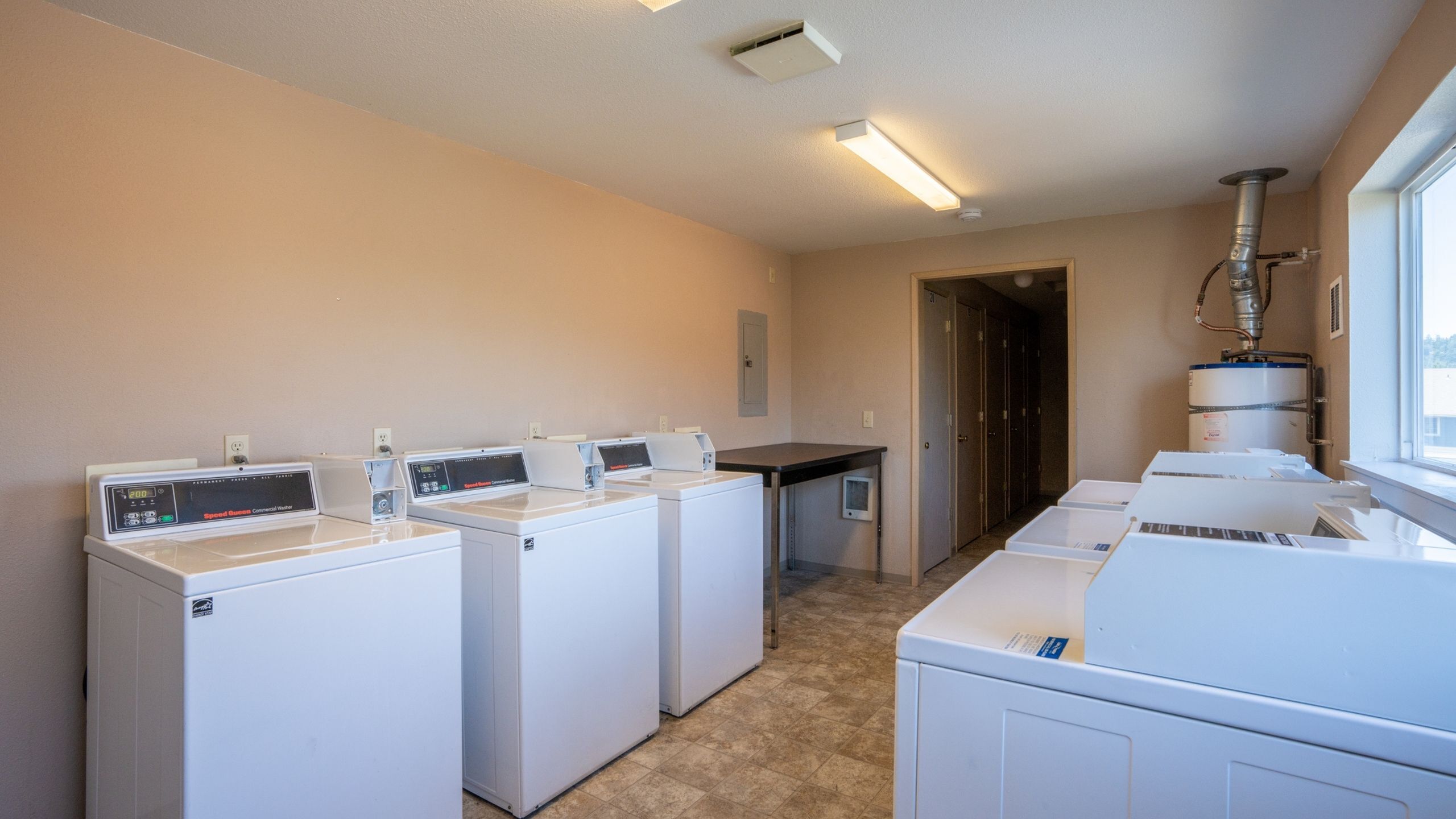 Modern laundry room with multiple washing machines, ample space, and natural light creating a functional and welcoming environment.