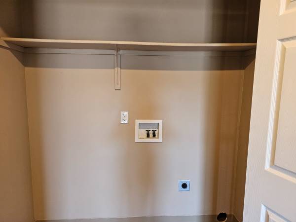 Bright laundry area with utility hookups and ample shelving space, perfect for organizing.