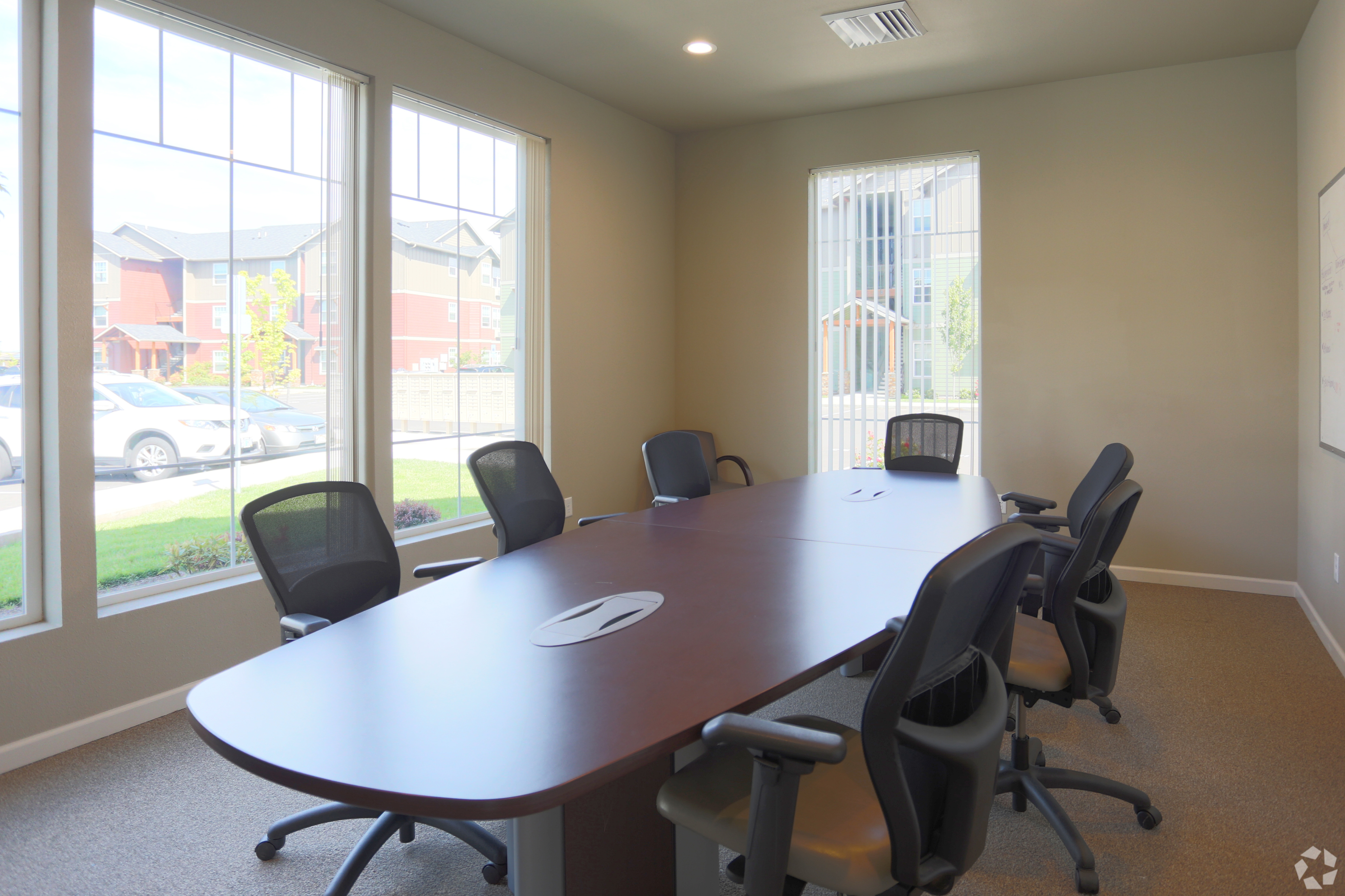 Bright and modern conference room with a large wooden table, ergonomic chairs, and ample natural light from expansive windows.