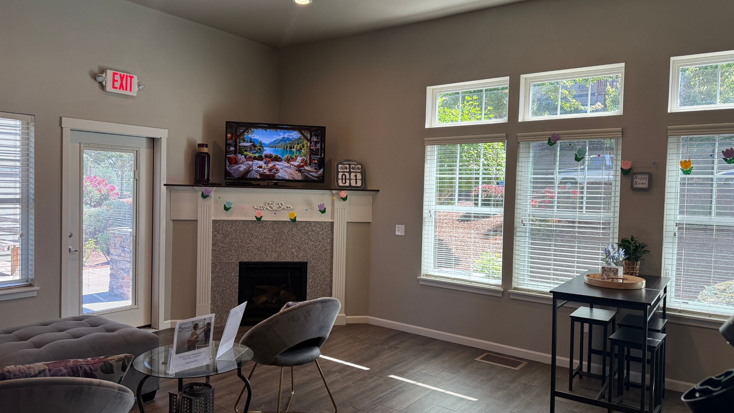 Inviting living room with modern decor, featuring a cozy fireplace, mounted TV, and large windows offering a bright and airy atmosphere.