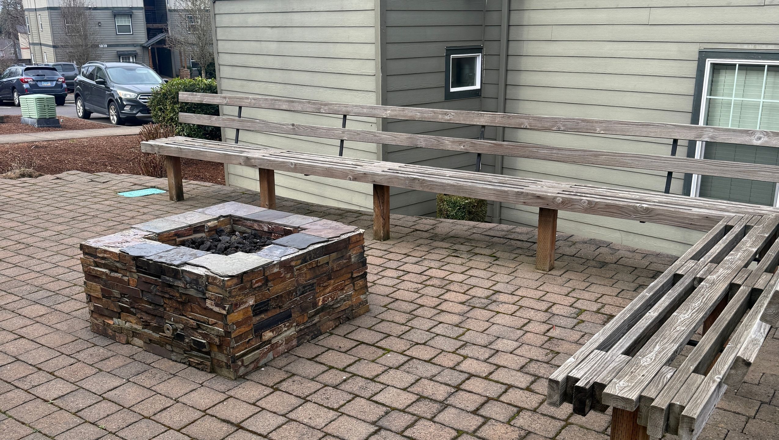 Charming outdoor patio with a rustic stone fire pit and wooden seating, perfect for cozy gatherings.