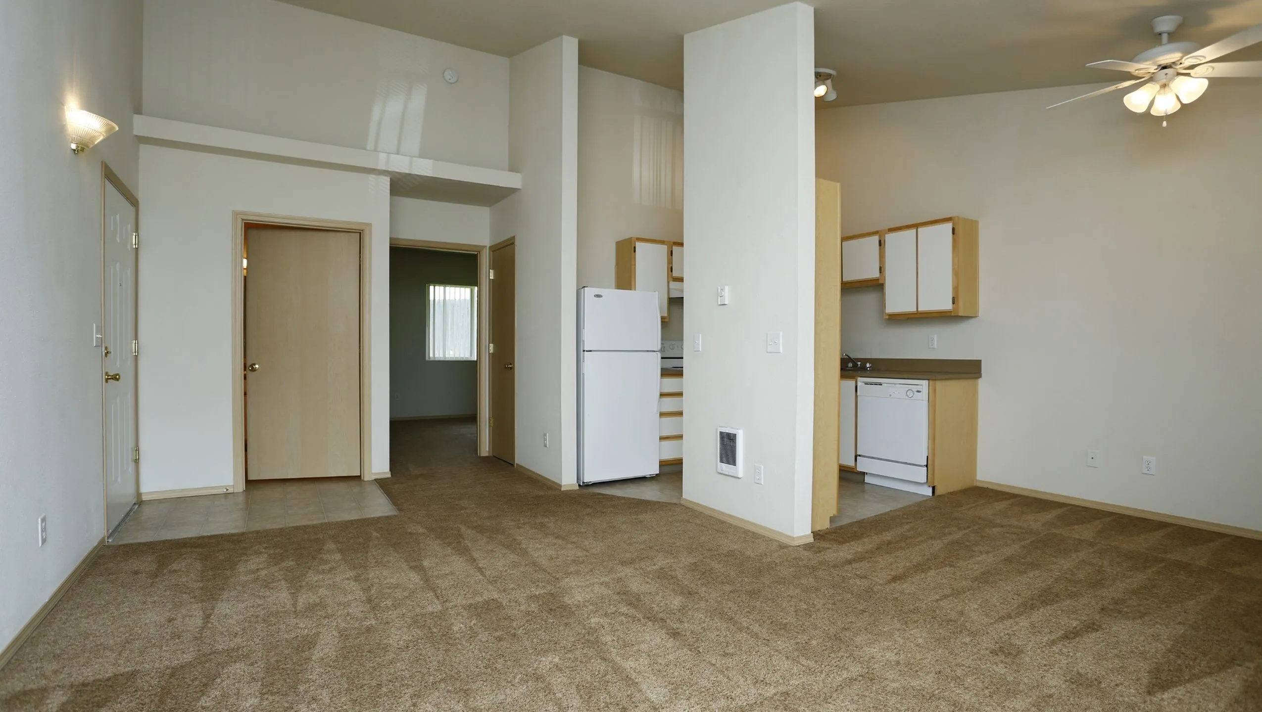 Inviting apartment interior featuring a cozy living area with plush carpet, modern kitchen with essential appliances, and warm natural lighting.