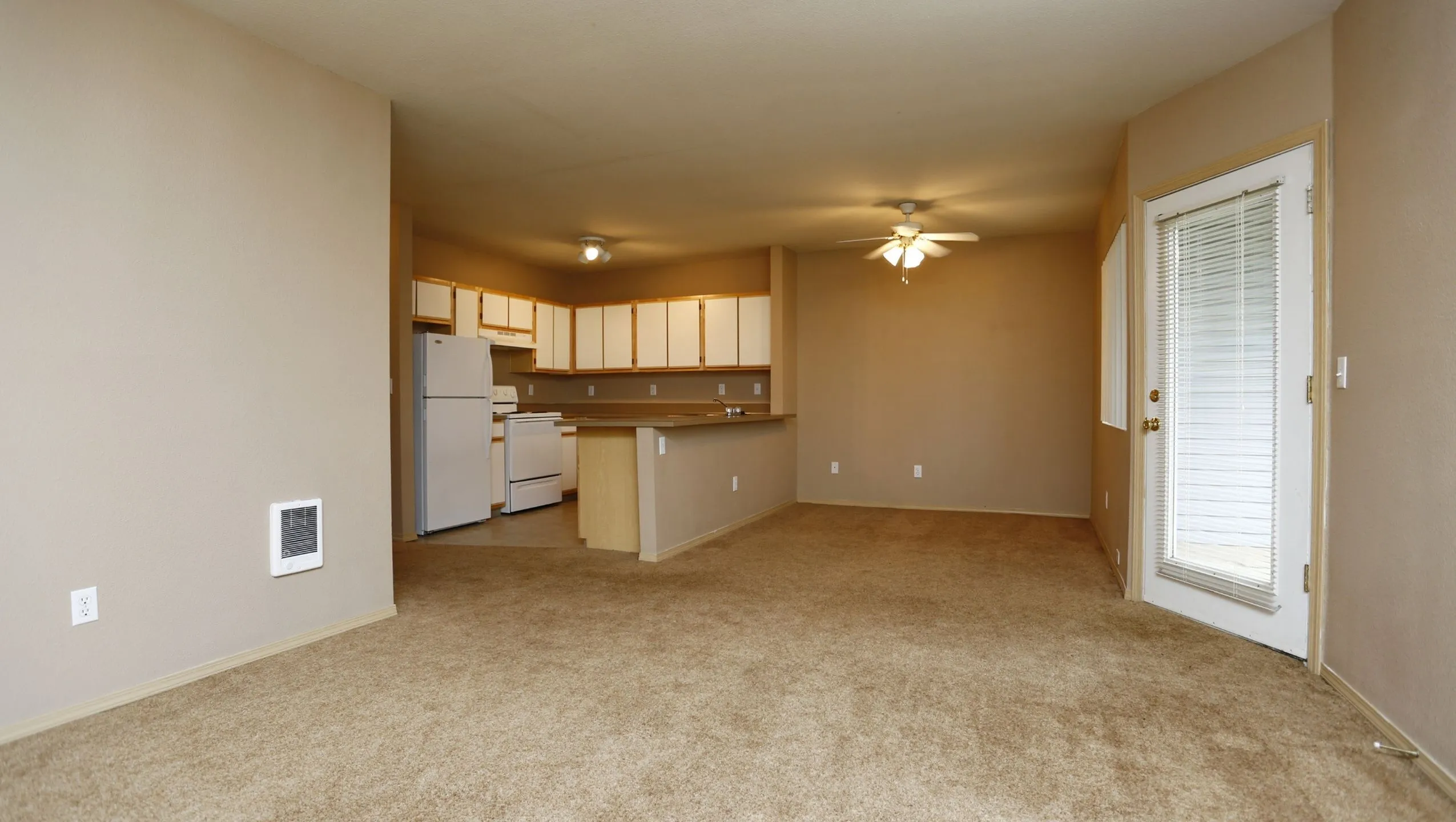 Inviting open-concept living area with plush carpet, plenty of natural light, and a well-equipped kitchen perfect for hosting.