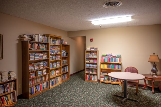 Cozy library nook with well-stocked bookshelves and a comfortable reading area illuminated by warm lighting.