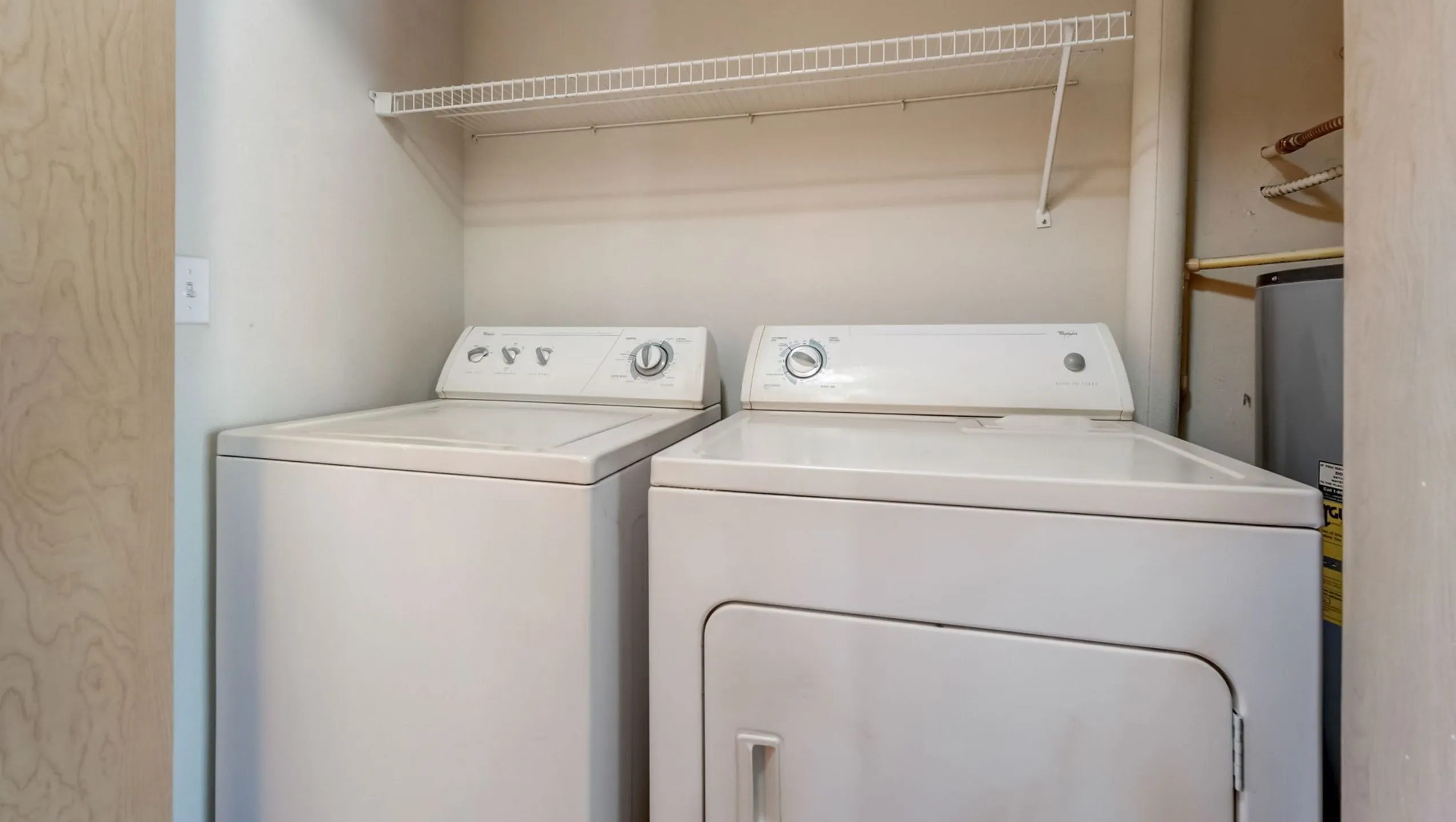 Convenient in-home laundry nook featuring a modern washer and dryer set with ample shelf space.