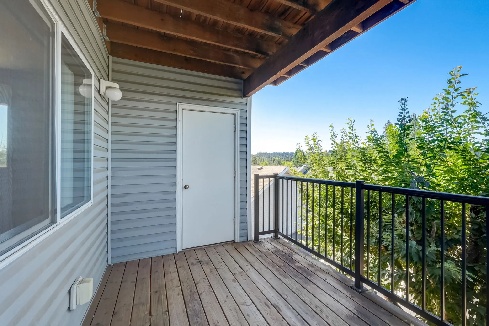 Charming balcony with wood flooring and lush green views, perfect for outdoor relaxation.
