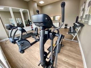 Modern fitness center featuring state-of-the-art exercise equipment, including ellipticals and treadmills, in a spacious and well-lit room with stylish decor.