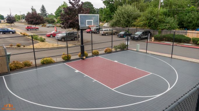 Modern outdoor basketball court with vibrant colors and secure fencing, perfect for recreational activities.