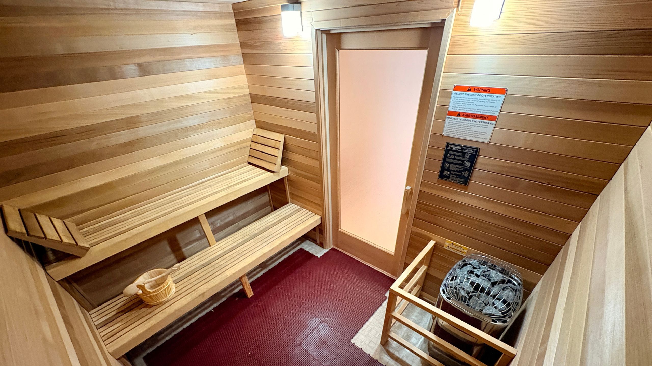 Luxurious wooden sauna room with stylish seating and a modern heater, perfect for relaxation and wellness.