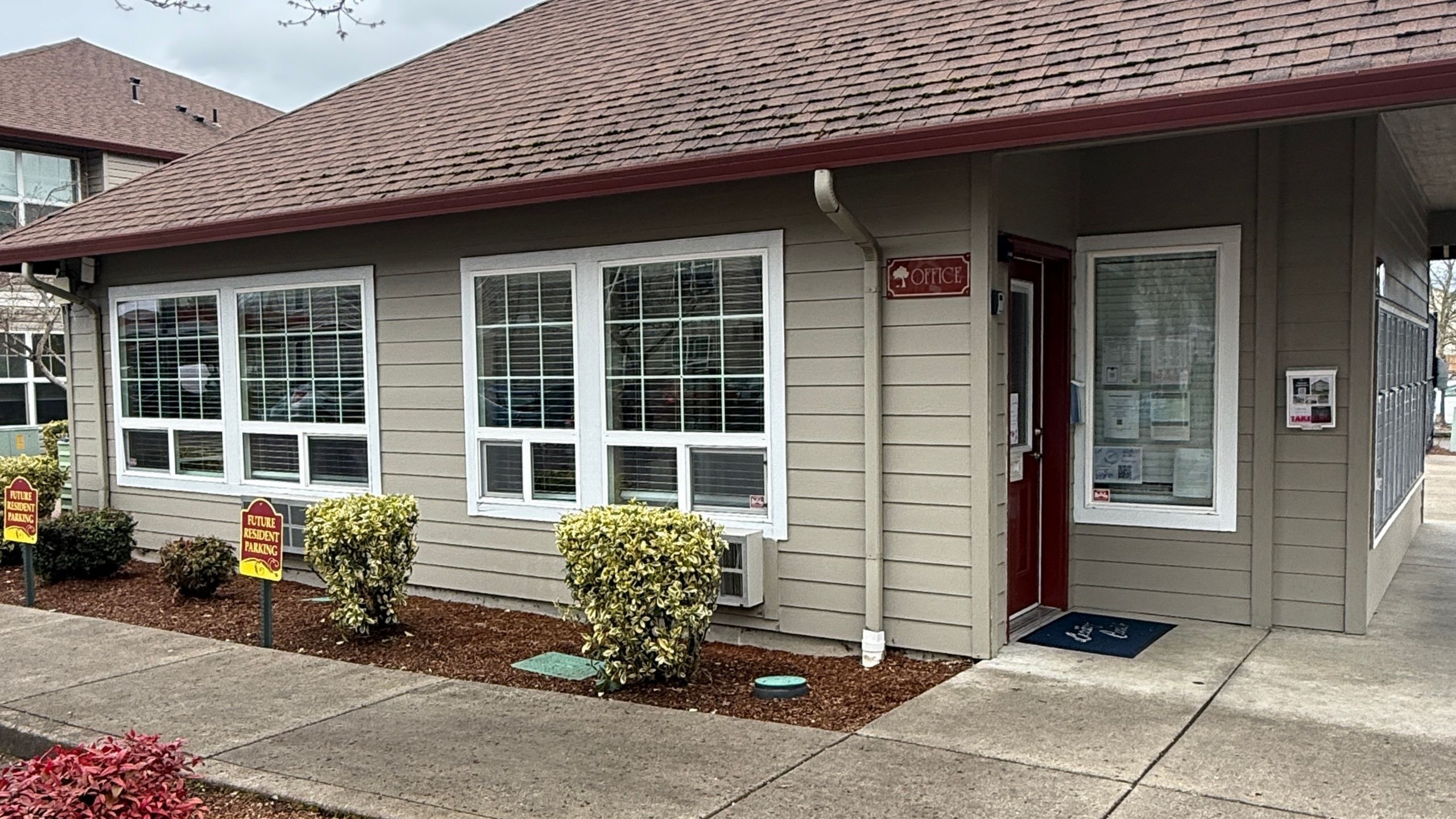 Charming apartment office exterior with modern siding, welcoming entryway, and well-manicured landscaping, ideal for prospective residents.