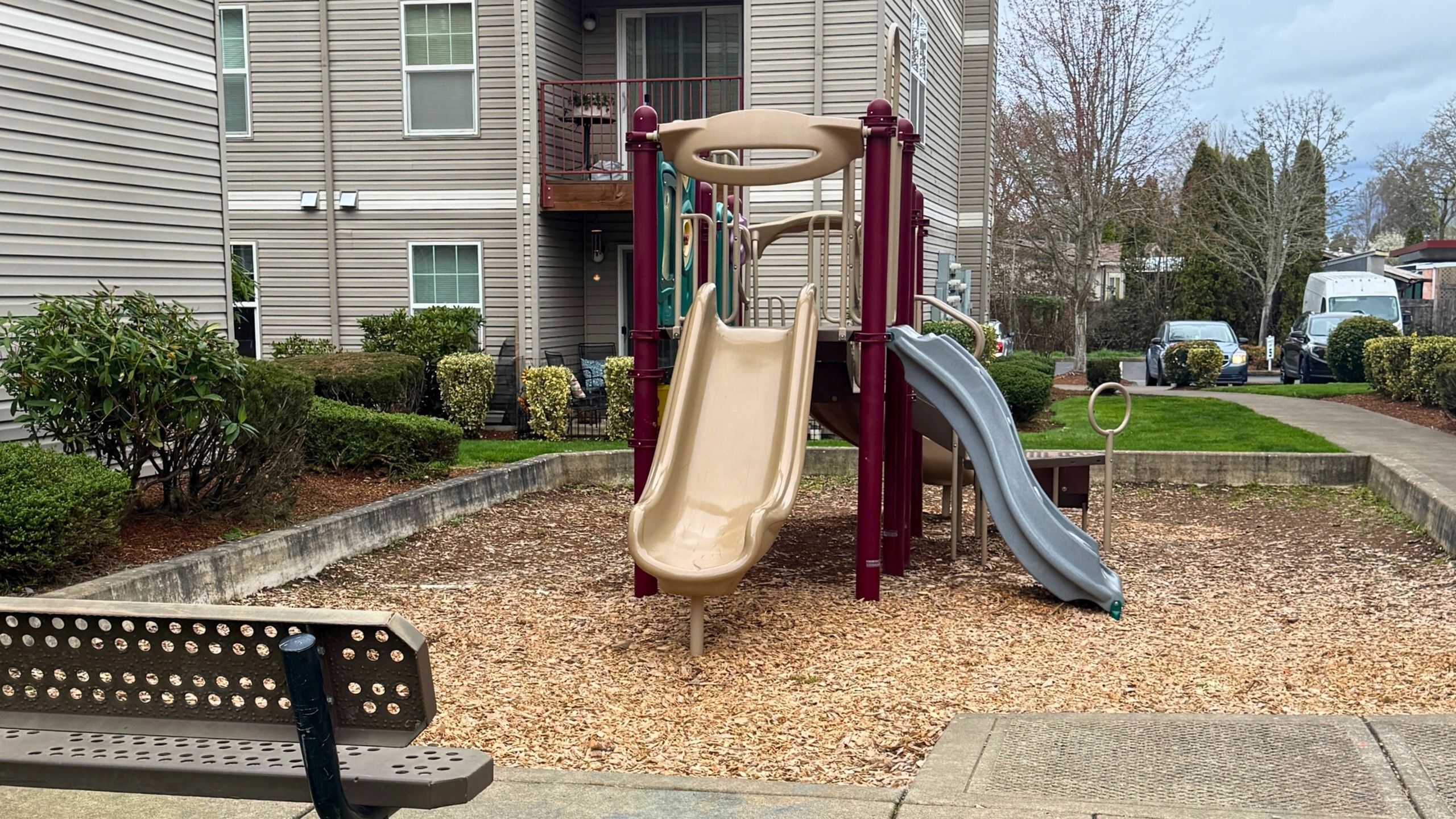 Charming apartment complex with modern playground and lush landscaping, perfect for family living.