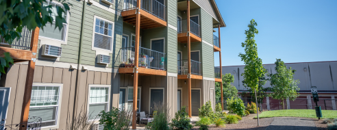 Charming apartment building with private balconies, lush landscaping, and modern architectural design.