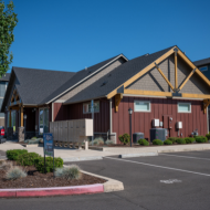 Charming suburban apartment building with rustic wood accents and well-maintained landscaping under a clear blue sky.