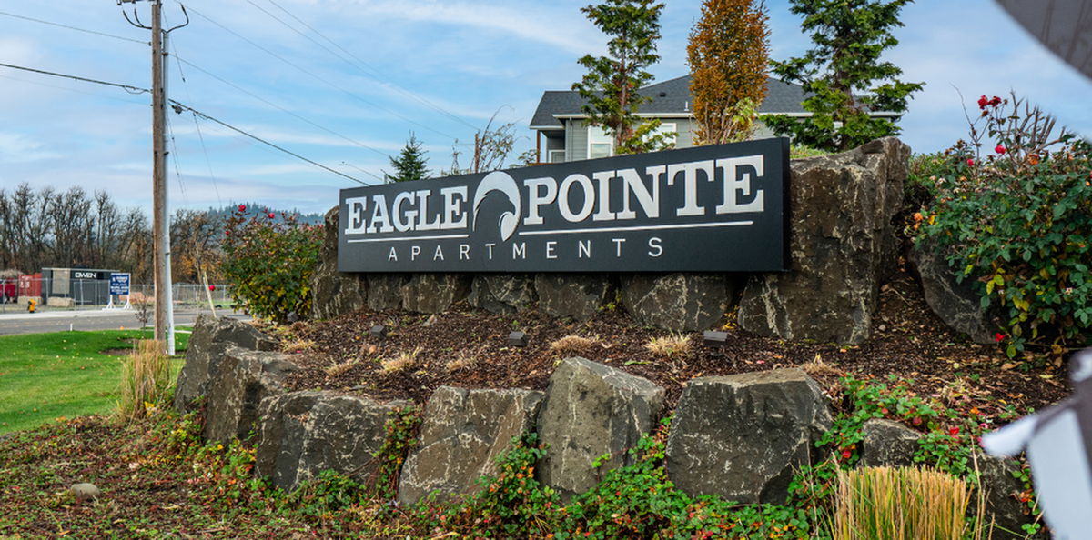Inviting entrance of Eagle Pointe Apartments, surrounded by lush greenery and natural stone landscaping.