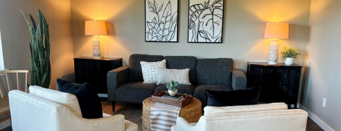 Chic and inviting living room with stylish decor, featuring a dark gray sofa, two elegant armchairs, and modern lighting.