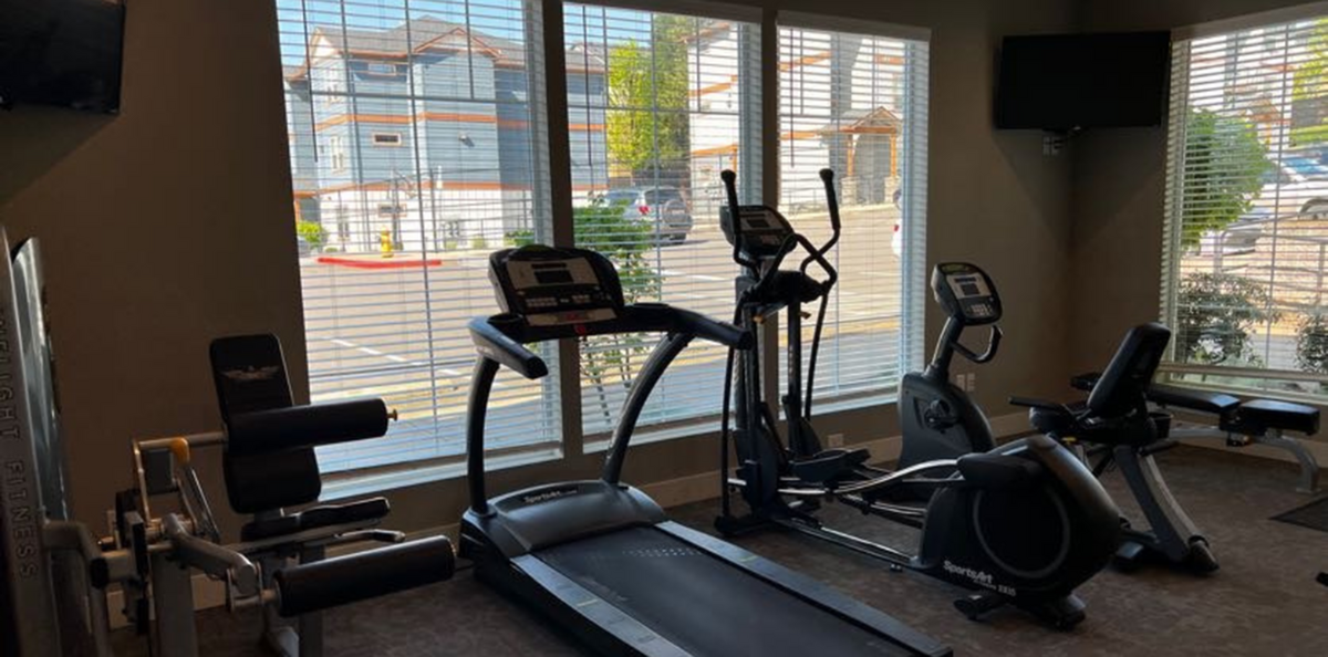 Modern fitness center featuring state-of-the-art cardio machines and strength equipment, with large windows offering a bright, inviting atmosphere.