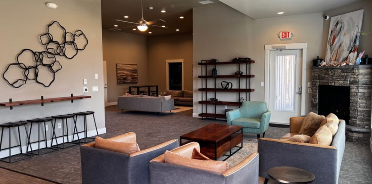 Elegant living room with modern decor, featuring cozy seating, stylish wall art, and a stone fireplace.