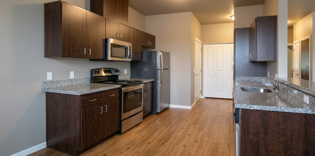 Modern kitchen with sleek stainless steel appliances, elegant dark wood cabinetry, and spacious granite countertops, complemented by warm hardwood flooring.