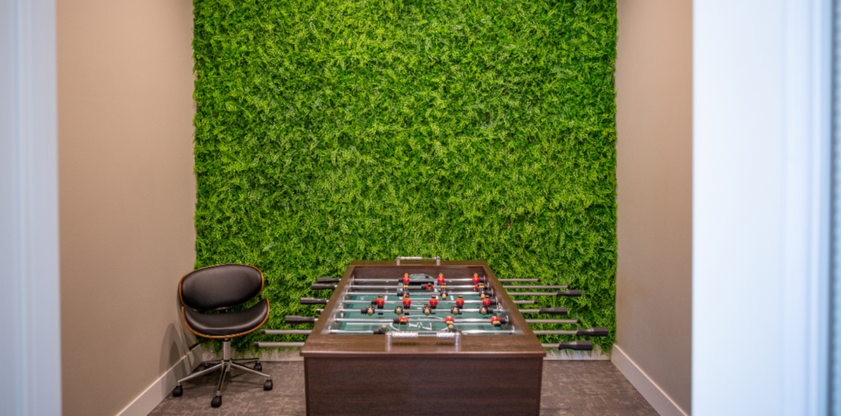 Chic recreation room with a foosball table and vibrant green wall, perfect for relaxation and entertainment.